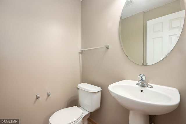 half bath featuring visible vents, a sink, and toilet