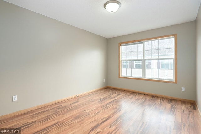 spare room featuring baseboards and wood finished floors