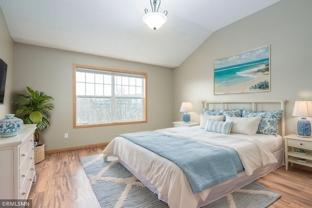 bedroom with vaulted ceiling, light wood-style flooring, and baseboards