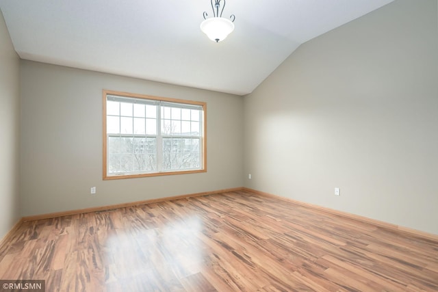 unfurnished room with lofted ceiling, baseboards, and wood finished floors