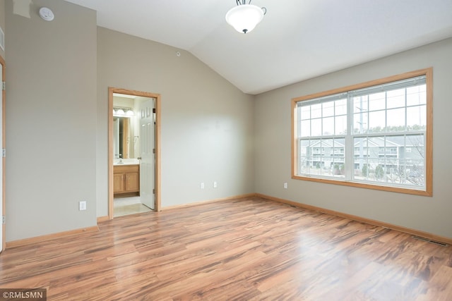 unfurnished bedroom with light wood-style floors, lofted ceiling, and baseboards