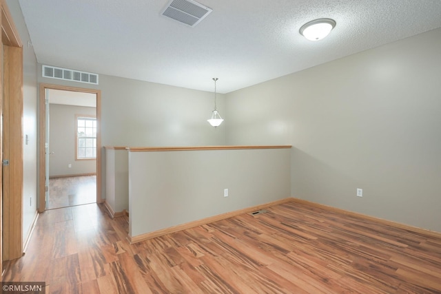 spare room with light wood-type flooring, visible vents, and baseboards