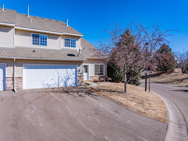 view of front of home with stone siding, aphalt driveway, roof with shingles, and an attached garage