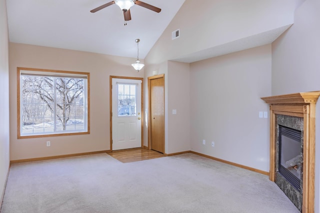 unfurnished living room with carpet floors, visible vents, a premium fireplace, high vaulted ceiling, and baseboards