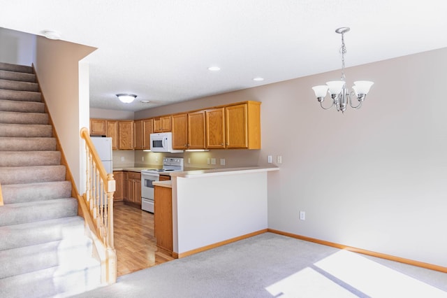 kitchen featuring light countertops, an inviting chandelier, white appliances, a peninsula, and baseboards