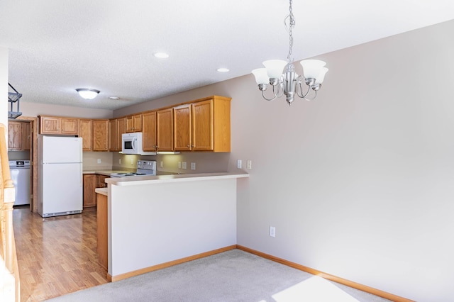 kitchen with a peninsula, white appliances, baseboards, light countertops, and hanging light fixtures