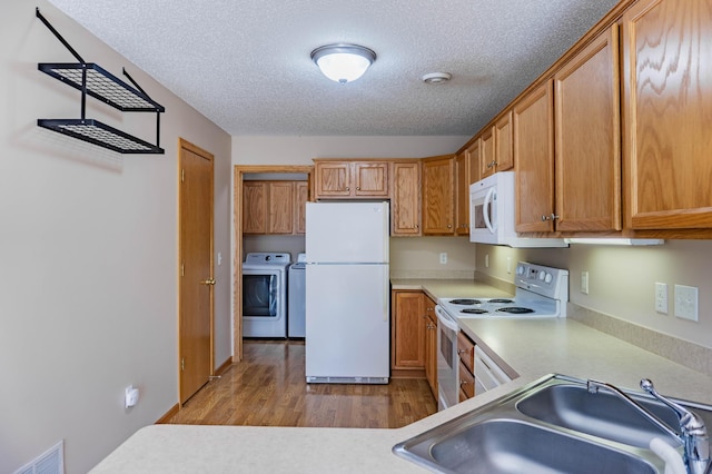 kitchen with white appliances, light countertops, light wood-style floors, washing machine and dryer, and a sink