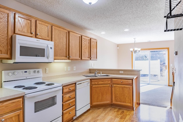 kitchen featuring light countertops, light wood-style flooring, a sink, white appliances, and a peninsula