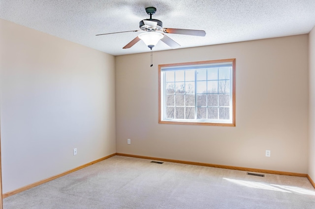 spare room featuring baseboards, visible vents, a textured ceiling, and carpet flooring