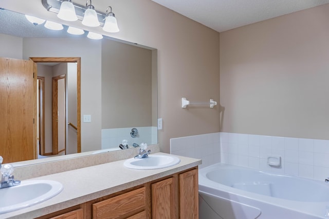 full bath featuring a textured ceiling, double vanity, a sink, and a bath