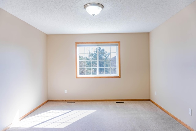 unfurnished room with carpet, visible vents, a textured ceiling, and baseboards