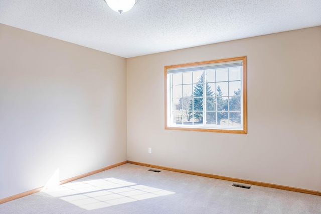 unfurnished room featuring carpet floors, visible vents, a textured ceiling, and baseboards