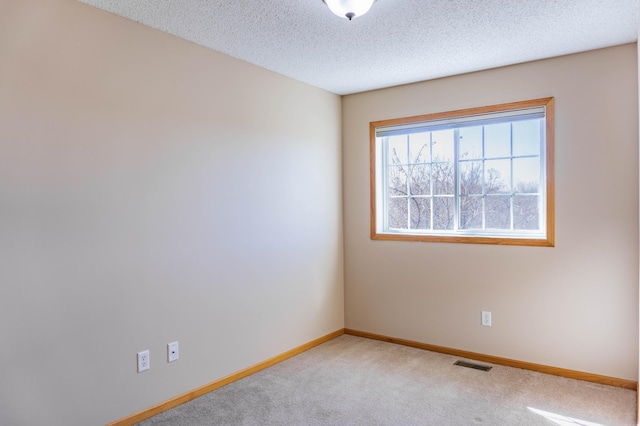 unfurnished room featuring carpet floors, baseboards, visible vents, and a textured ceiling