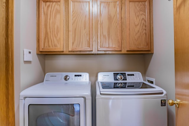 clothes washing area featuring cabinet space and washing machine and dryer