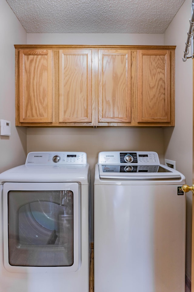 laundry room with a textured ceiling, cabinet space, and washer and dryer