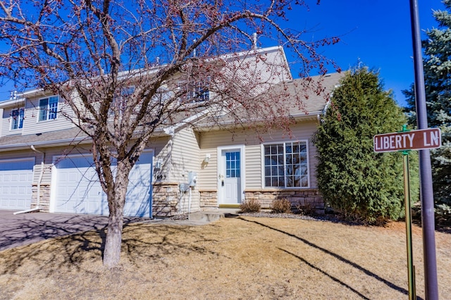 view of front facade with a garage, stone siding, and driveway