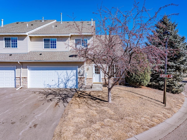 view of front of house with aphalt driveway, stone siding, a shingled roof, and an attached garage