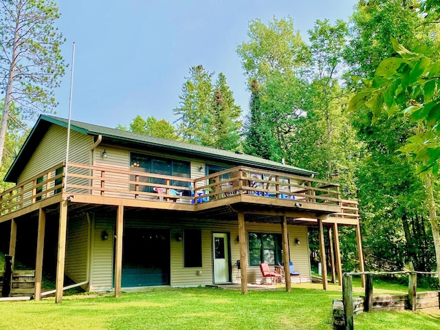 back of property with a lawn, an attached garage, and a wooden deck