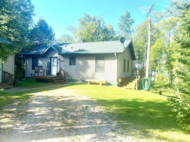 rear view of property featuring driveway and a lawn