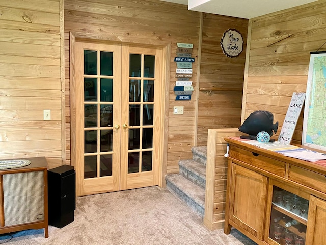 doorway to outside featuring french doors, stairway, light colored carpet, and wooden walls