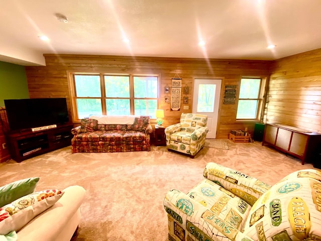 living room featuring wood walls, plenty of natural light, and carpet flooring