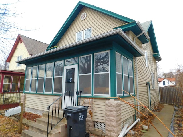 view of side of property with a sunroom and fence