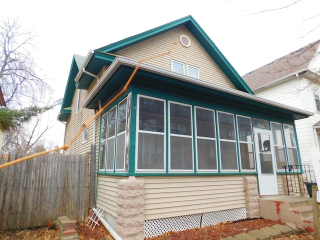 view of side of home with a sunroom and fence