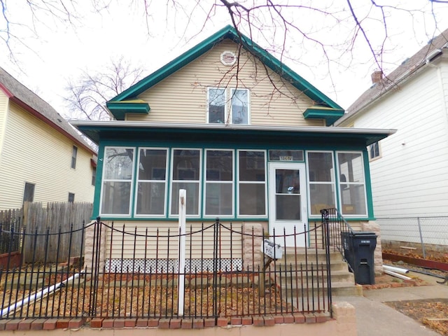 rear view of property with fence and a sunroom