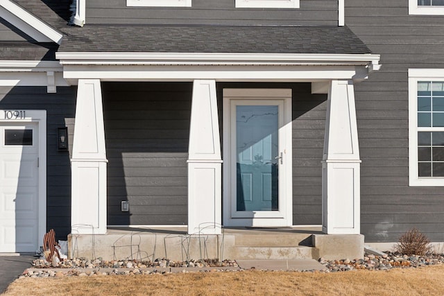 view of exterior entry with a shingled roof