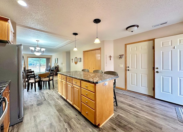 kitchen featuring freestanding refrigerator, a center island, a breakfast bar area, and wood finished floors