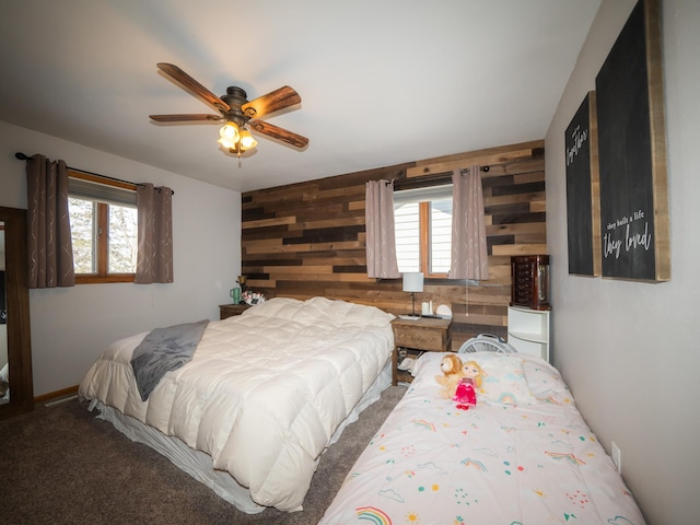 bedroom with carpet flooring, wood walls, ceiling fan, and multiple windows