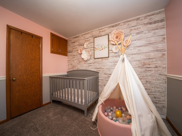 unfurnished bedroom featuring a closet, baseboards, a crib, and carpet