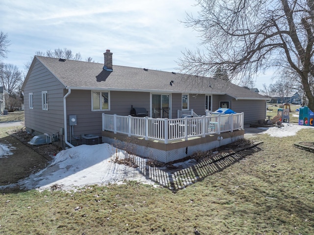 rear view of property with a chimney, a deck, and roof with shingles