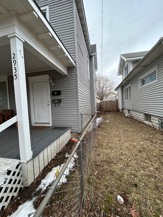 view of side of home with covered porch and fence