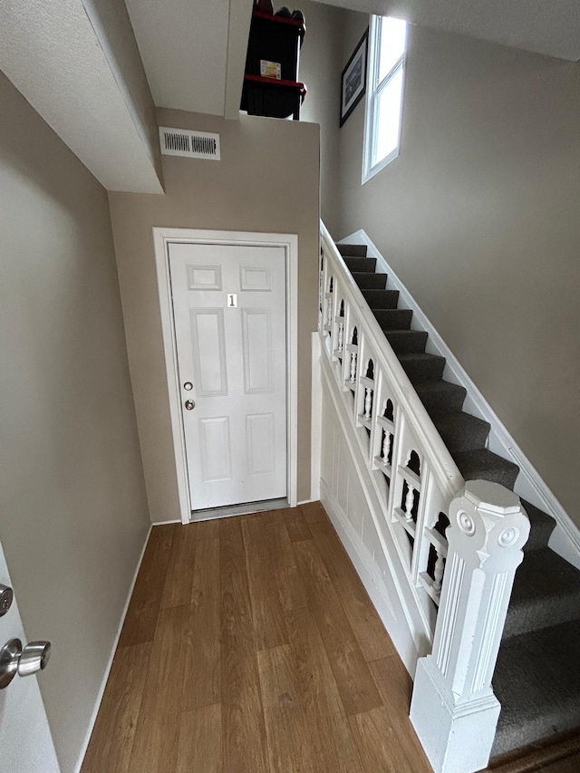 entryway featuring stairs, wood finished floors, visible vents, and baseboards