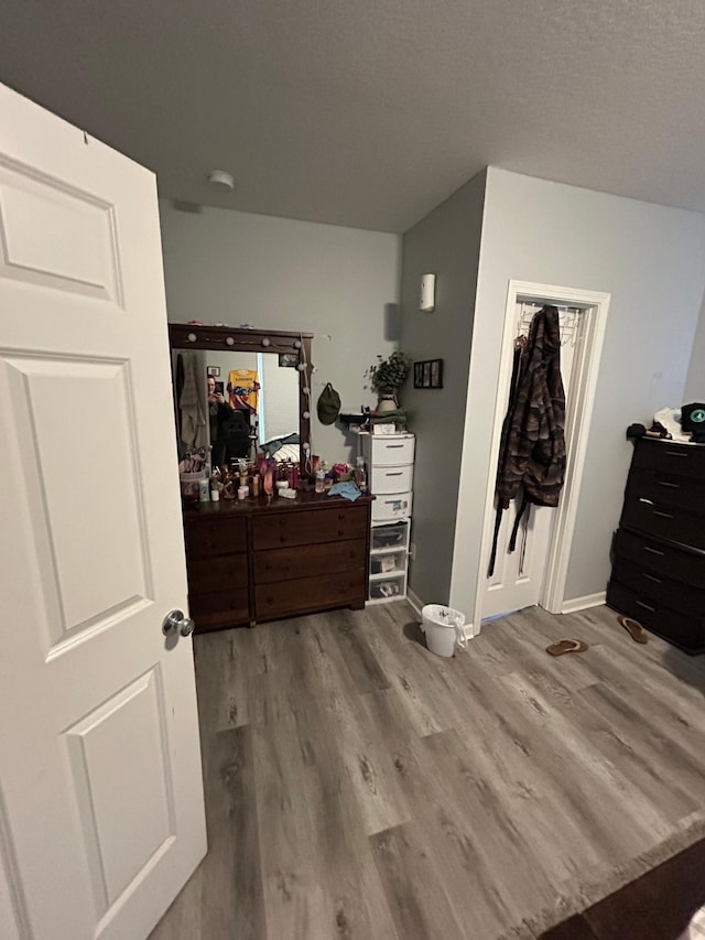 bedroom with a textured ceiling, wood finished floors, and baseboards