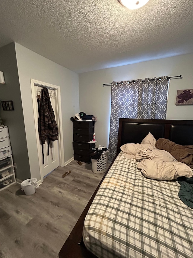 bedroom with a textured ceiling, wood finished floors, and baseboards