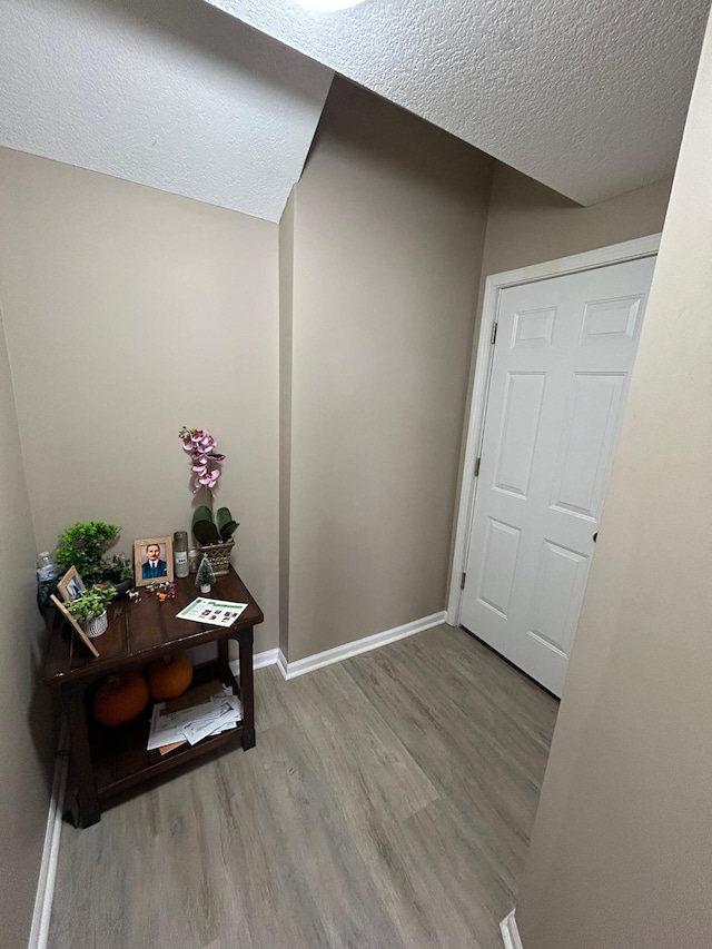 interior space with a textured ceiling, baseboards, and wood finished floors