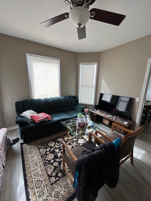 living area featuring a ceiling fan, a healthy amount of sunlight, a textured ceiling, and wood finished floors