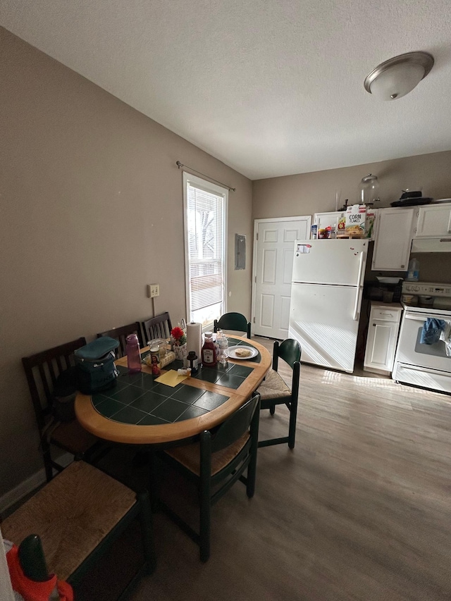 dining area with a textured ceiling and wood finished floors