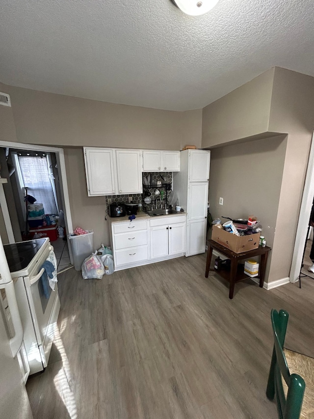 kitchen with white appliances, white cabinetry, a sink, and wood finished floors