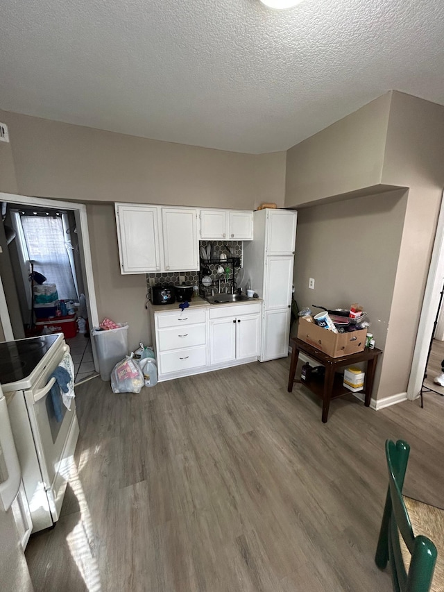 kitchen featuring white electric range oven, white cabinetry, a sink, a textured ceiling, and wood finished floors