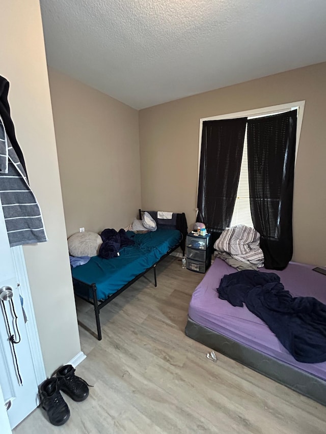 bedroom with a textured ceiling and wood finished floors