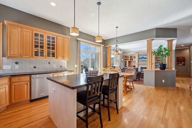 kitchen with a kitchen island, glass insert cabinets, light wood-type flooring, decorative backsplash, and stainless steel dishwasher