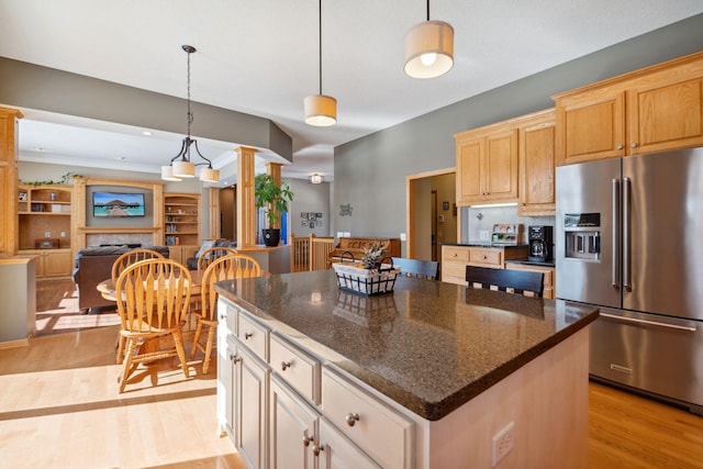 kitchen with ornate columns, a fireplace, stainless steel fridge with ice dispenser, light wood-style floors, and decorative light fixtures