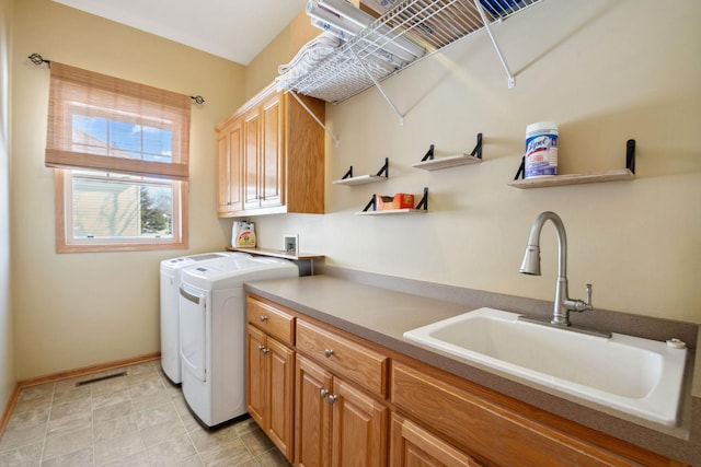 clothes washing area featuring visible vents, a sink, cabinet space, baseboards, and washing machine and clothes dryer