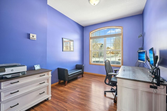 office area with baseboards, dark wood-type flooring, and a textured ceiling