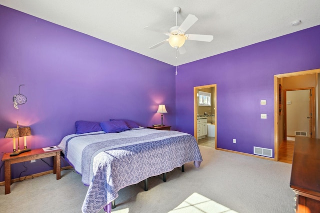 carpeted bedroom with ensuite bath, visible vents, baseboards, and ceiling fan