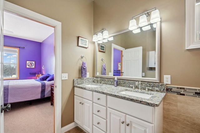 ensuite bathroom featuring double vanity, connected bathroom, and a sink