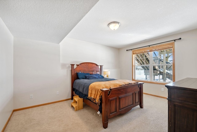 bedroom featuring light colored carpet, baseboards, and a textured ceiling